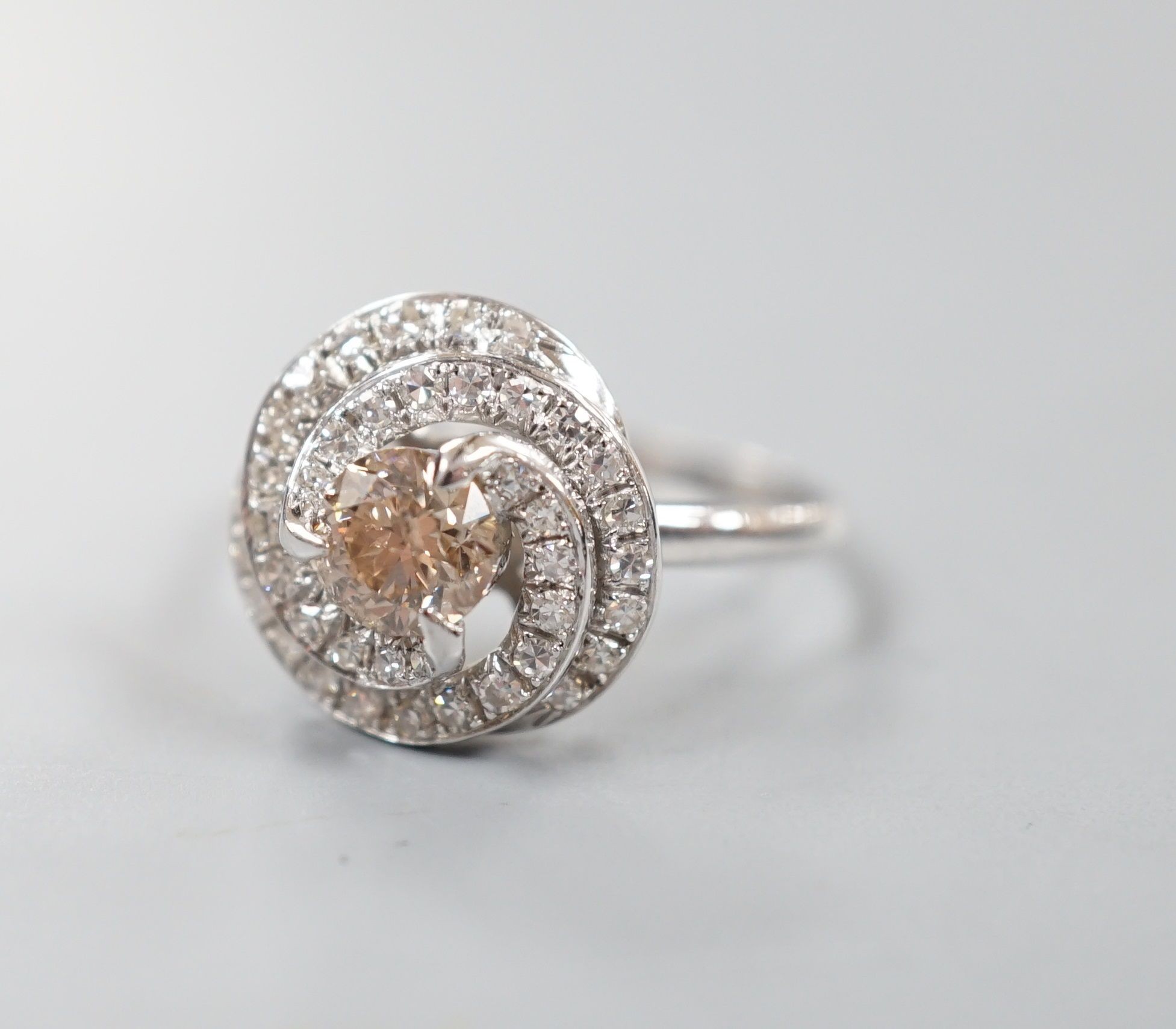 A French white metal(18ct poincon mark) and cognac coloured single stone diamond ring, with diamond set spiral cluster setting, size S, gross 5.5 grams.